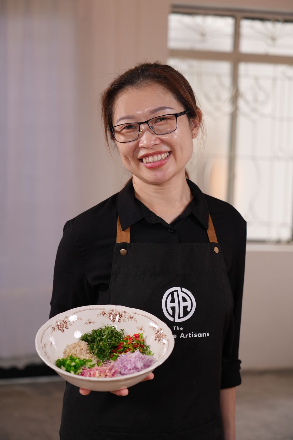 Nyonya Su Pei holding a bowl of freshly chopped herbs, chilli and shallots